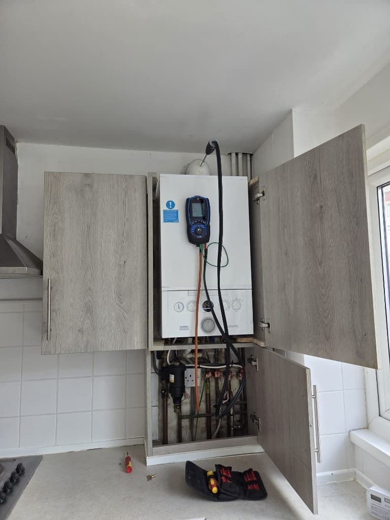 Ideal boiler being serviced inside a kitchen cupboard in Torbay